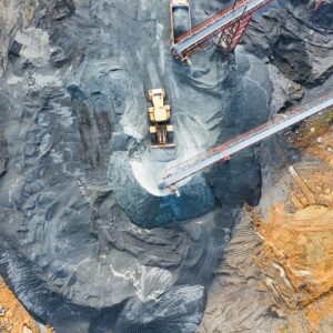 Aerial view of a large industrial mining site with heavy machinery and conveyor belts in operation.