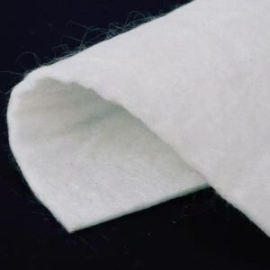 Primer plano de un geotextil de polipropileno que muestra su textura fibrosa no tejida y su estructura porosa para filtración y drenaje.